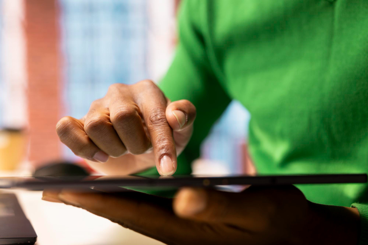 Empresário com tablet em mãos selecionando documentos para serem arquivados digitalmente por exigência legal.
