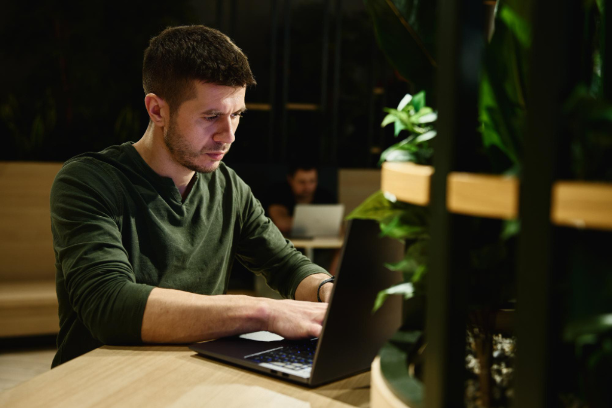 Homem sentado usando notebook sobre uma mesa em ambiente de escritório home office representando: Como emitir um certificado e-CNPJ A3 com token ou cartão.
