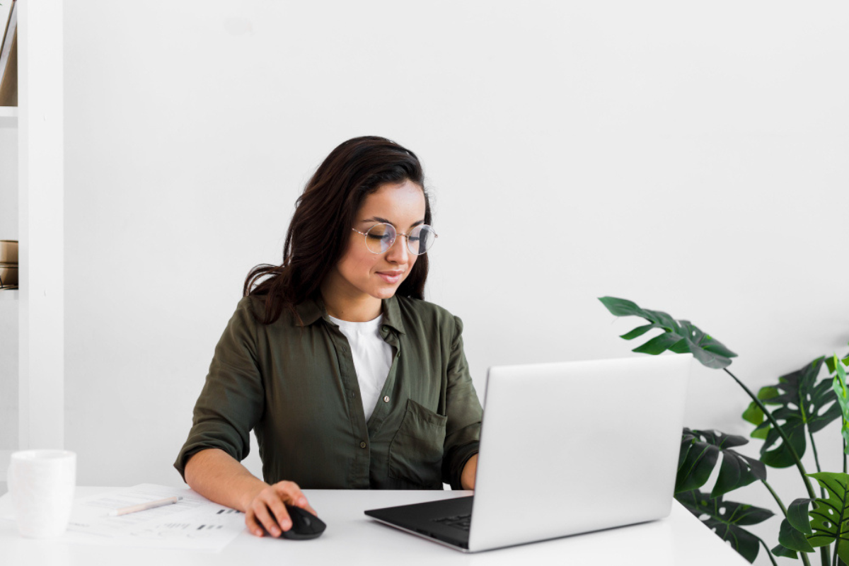Empresária sentada usando notebook sobre a mesa em ambiente de escritório representando: Passo a passo para instalar e configurar o e-CNPJ A3.