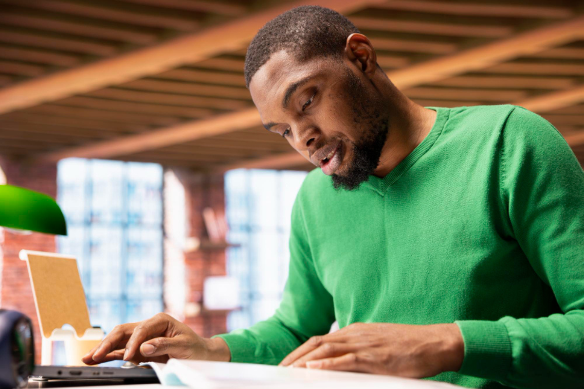 Homem analisando documentos sentado em frente a um notebook em um ambiente de escritório representando como funciona a assinatura digital com validade jurídica.