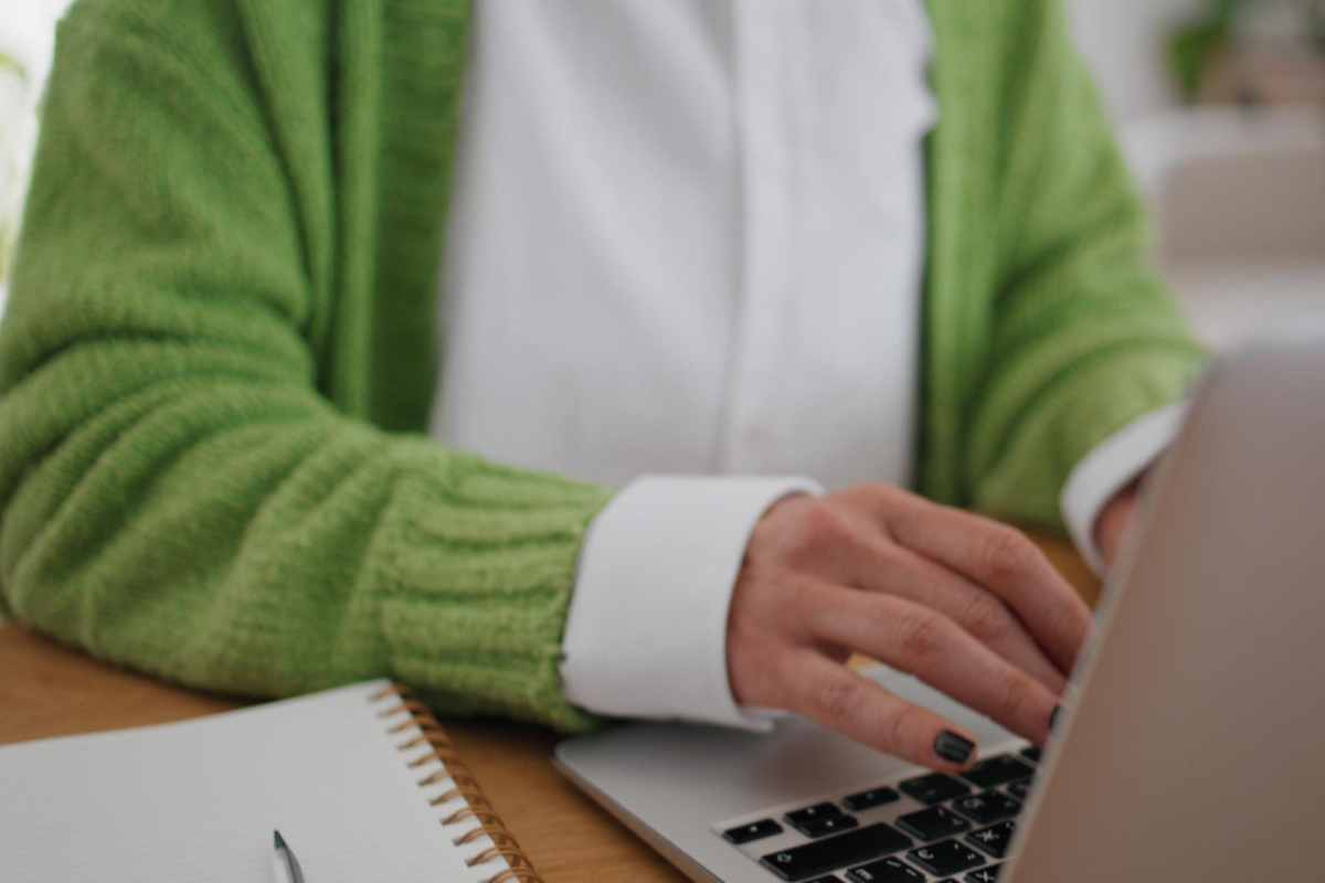 Mulher sentada usando notebook sobre a mesa em ambiente de escritório representando: Reforma Tributária: como a tributação no destino funciona?