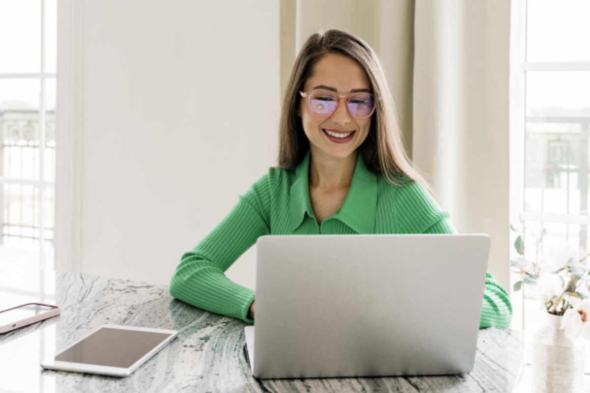 Mulher trabalhando em um notebook em ambiente de escritório representando: Reforma Tributária: o que muda no crédito e débito?