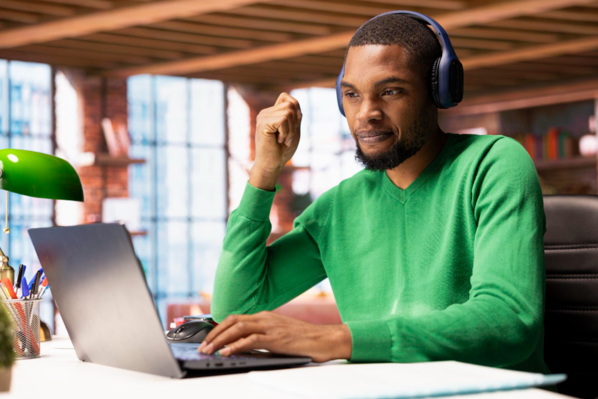 Homem sentado trabalhando em um notebook sobre uma mesa e de fone de ouvido em ambiente home office representando: Quando sua empresa precisa de um contador?