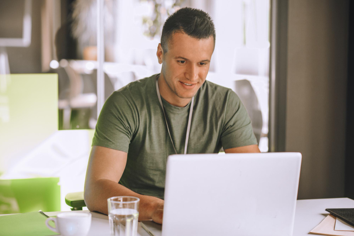 Homem sentado trabalhando em um notebook sobre uma mesa em ambiente de escritório representando: Gestão tributária e Reforma Tributária: alguma coisa muda?