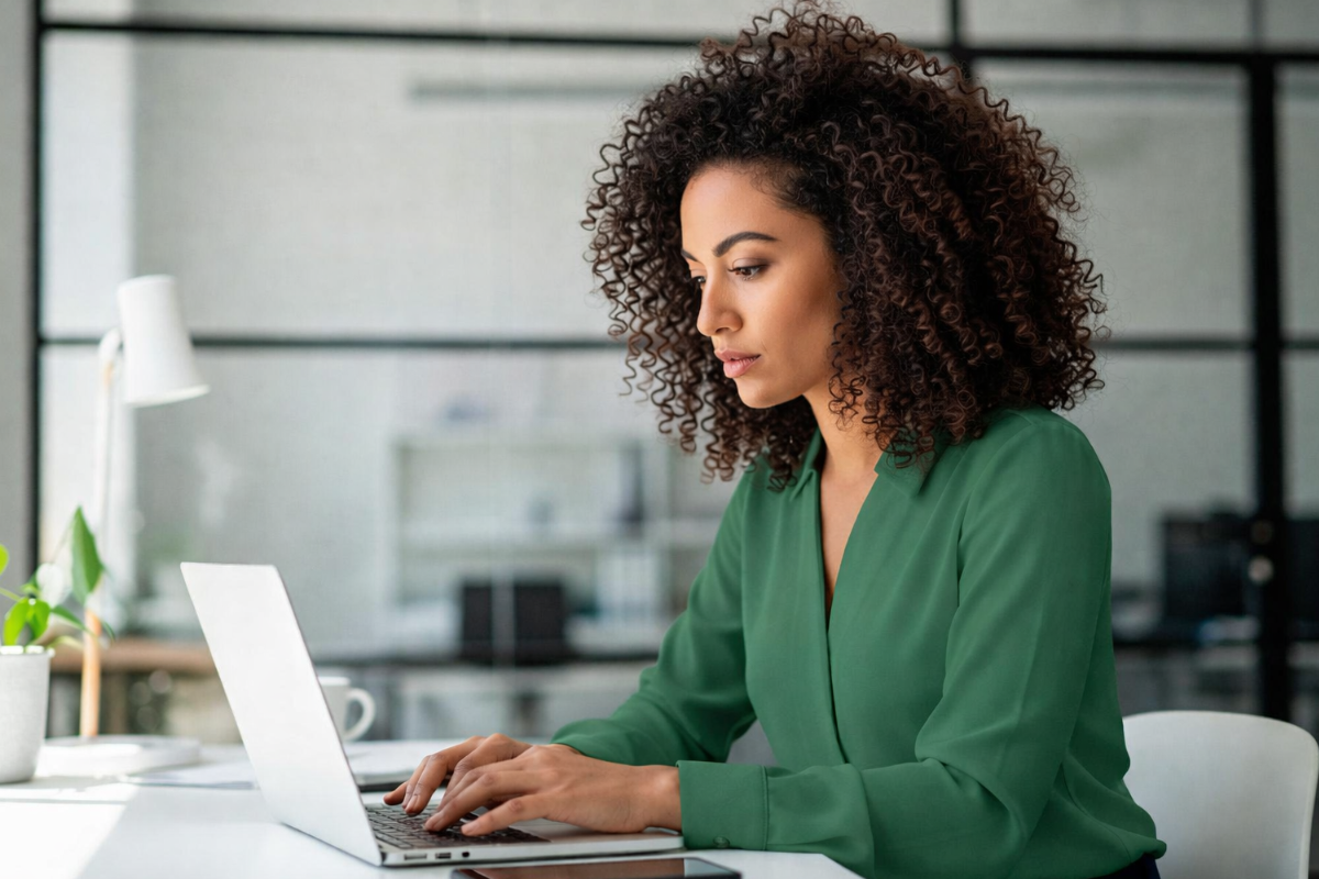 Mulher trabalhando em um notebook em ambiente de escritório representando: Compliance tributário e reforma: como proteger seu CNPJ?