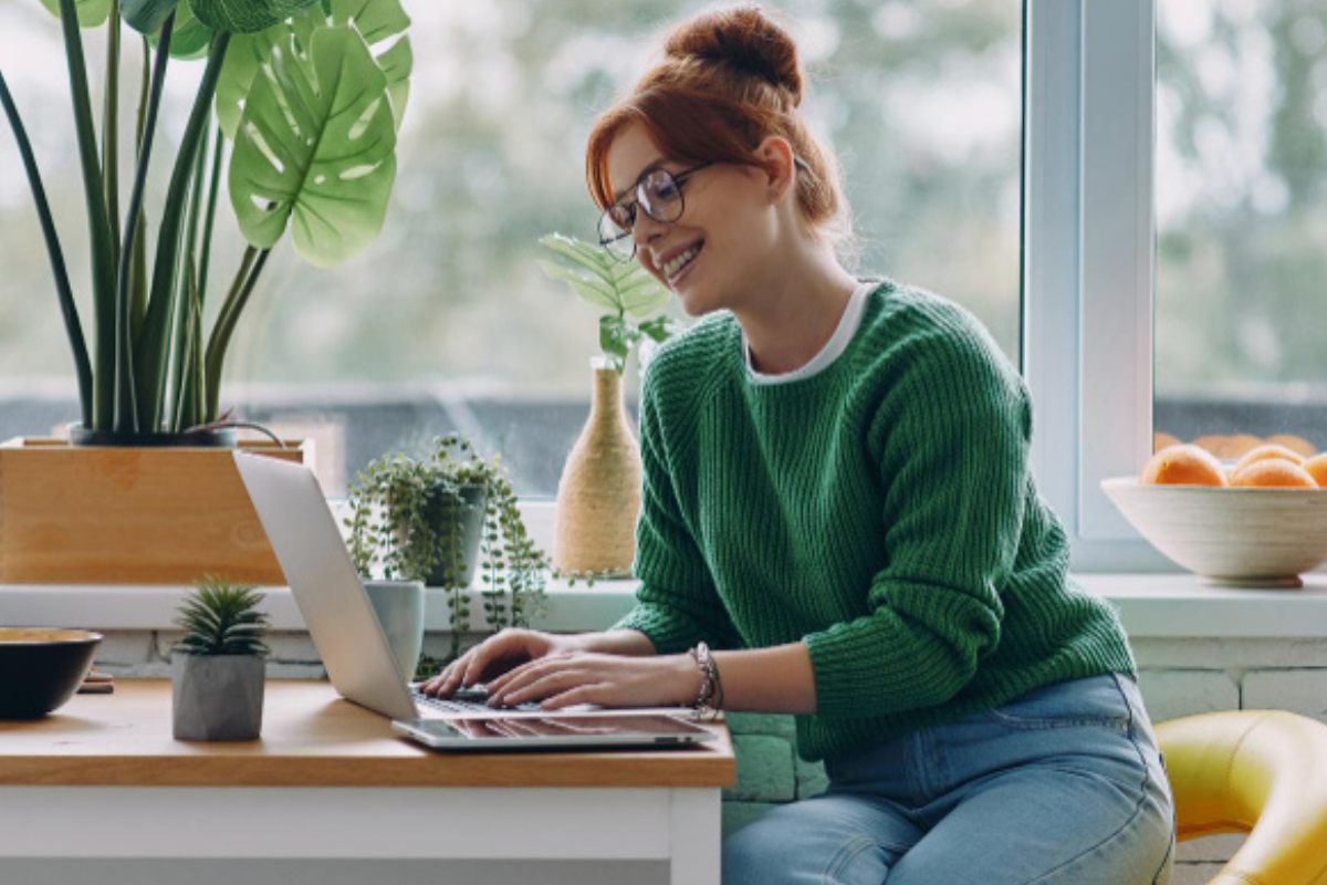 Mulher trabalhando em um notebook em ambiente de escritório representando: e-CAC, SPED, DCTFWeb e eSocial: por que o certificado digital é essencial.
