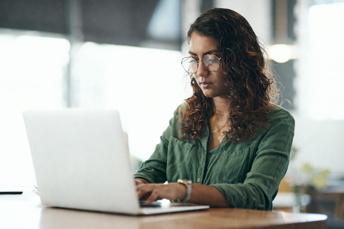 Mulher trabalhando em um notebook em ambiente de escritório representando: NFS-e Nacional 2026: o que muda e como garantir conformidade jurídica.