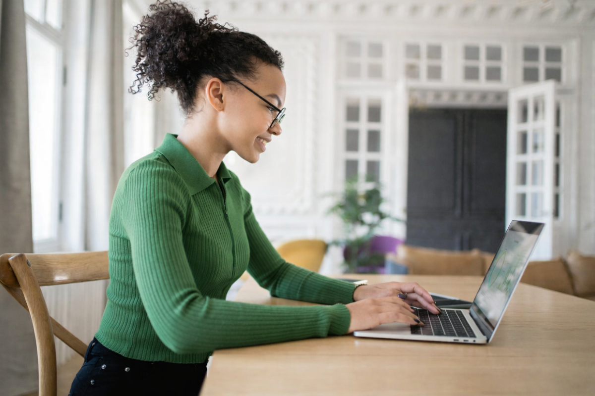 Mulher trabalhando em um notebook em ambiente de escritório representando: Fim da guerra fiscal: o que a Reforma Tributária resolve e o que permanece em disputa.