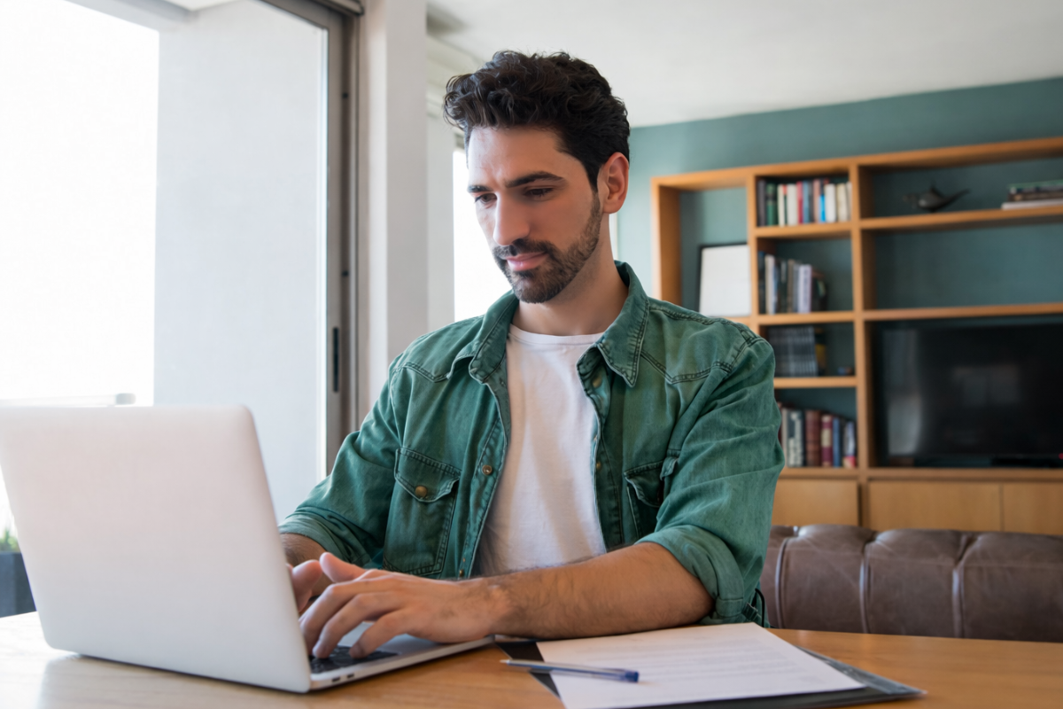 Homem usando notebook sobre uma mesa sentado em ambiente home office representando: Responsabilidade jurídica por erros fiscais em ambientes digitais: quem responde na reforma tributária?