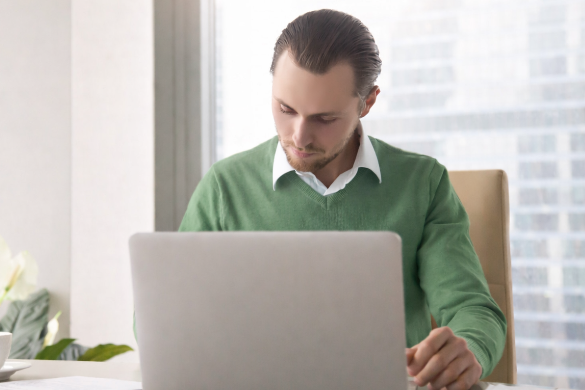 Homem usando notebook sobre uma mesa sentado em ambiente home office representando: Qual a função das obrigações acessórias no crédito tributário?