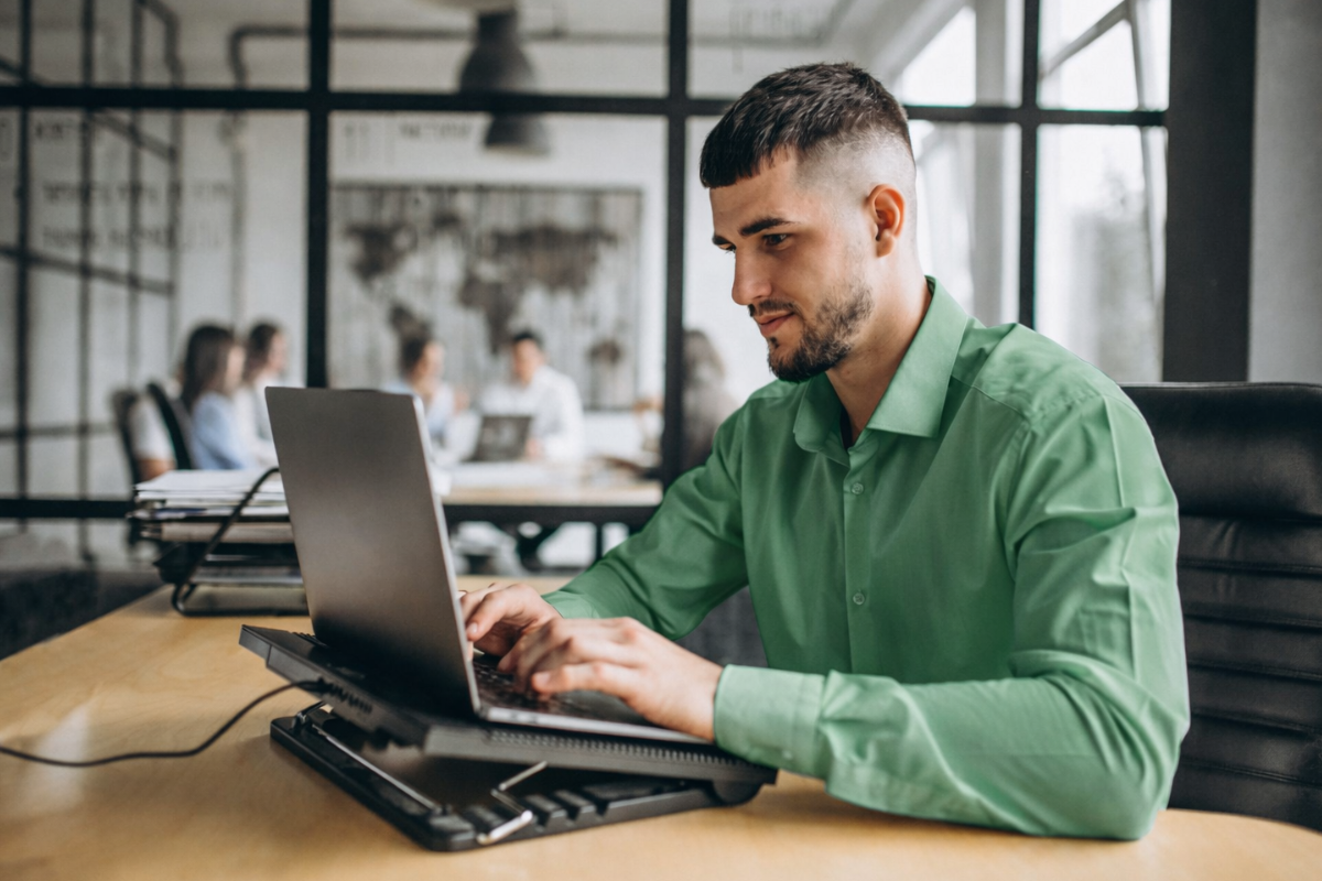 Homem usando notebook sobre uma mesa sentado em ambiente home office representando: A importância dos códigos fiscais na NF na Reforma Tributária.
