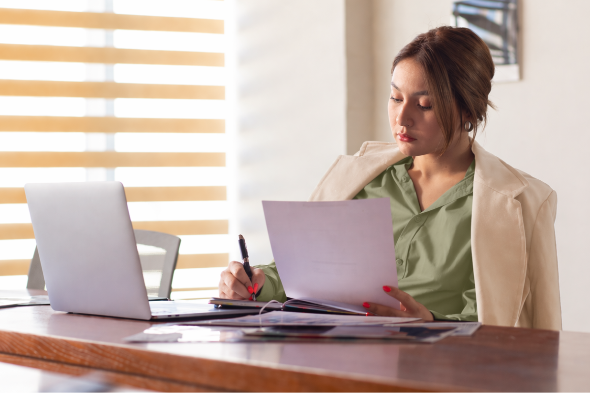 Mulher trabalhando em um notebook sobre uma mesa em ambiente de escritório representando: 6 sinais que seu escritório de contabilidade está desorganizado.