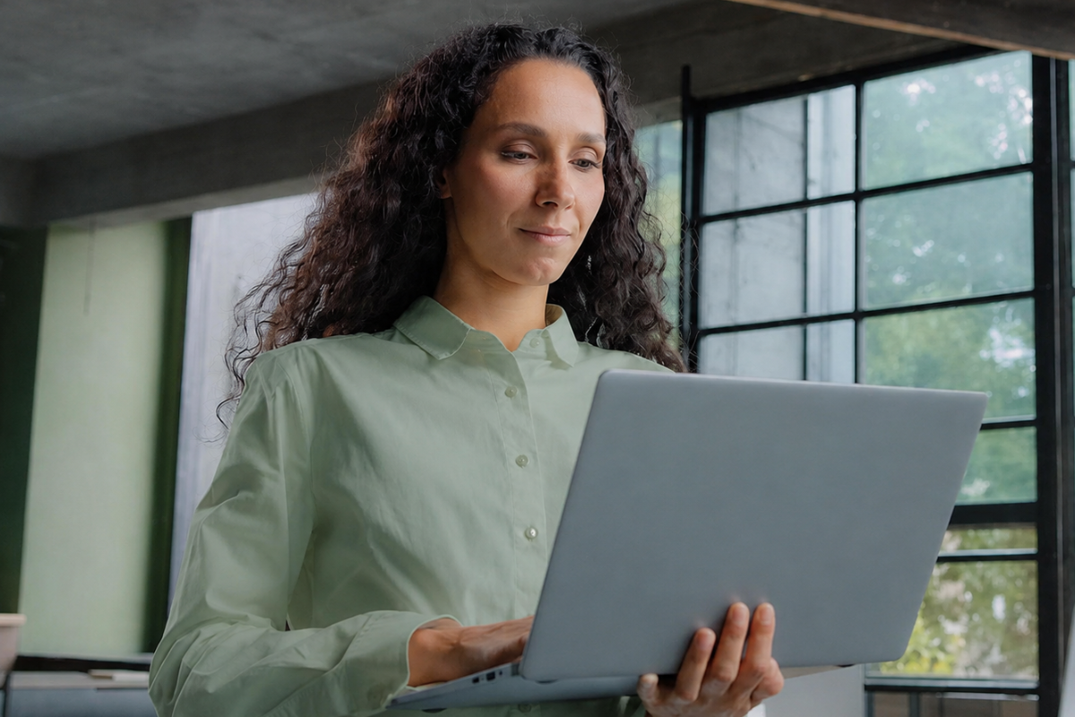 Mulher usando notebook em mãos e de pé em ambiente de escritório representando: Como integrar ERP com escritório contábil.
