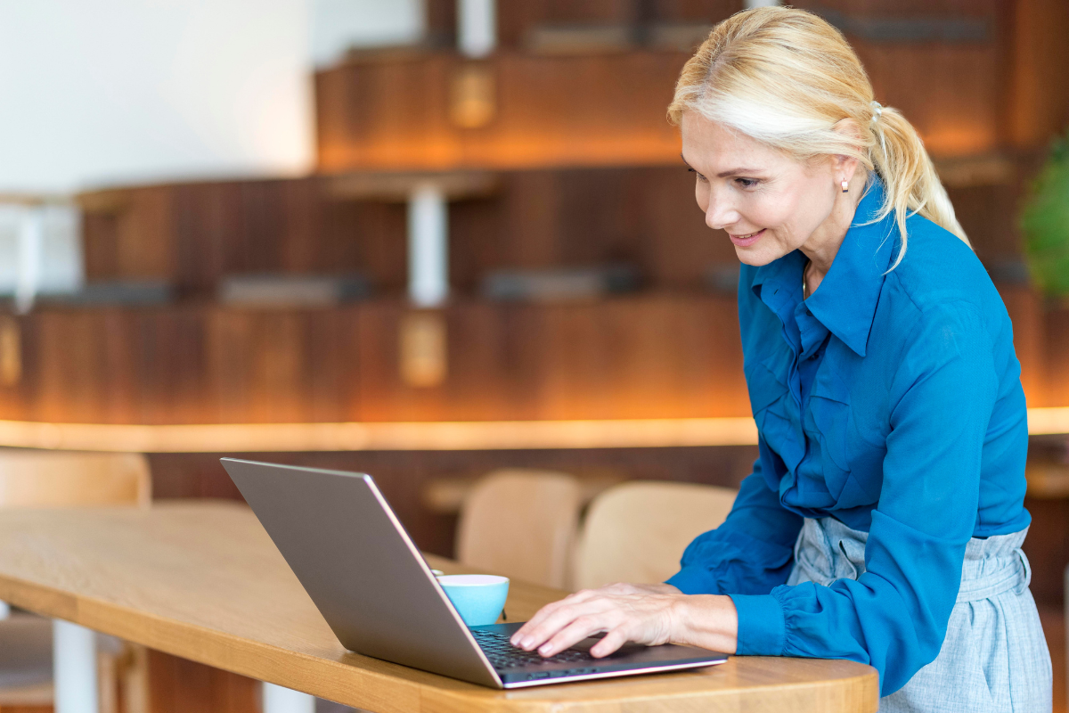 Mulher usando notebook em mãos e de pé em ambiente de escritório analisando Fiscalização eletrônica e identidade digital: de quem é a culpa?