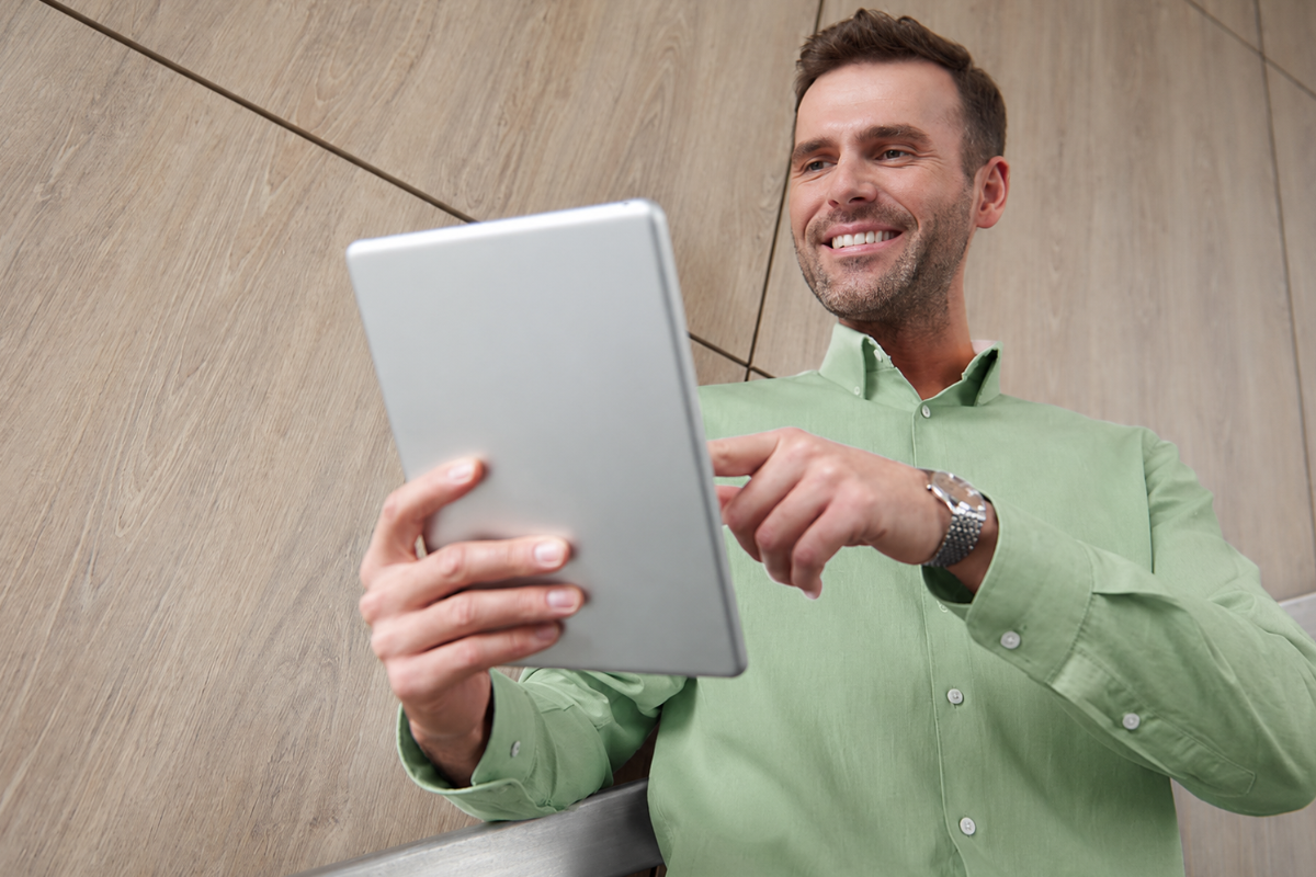 Homem em ambiente de trabalho andando e olhando para um tablet nas mãos representando: Quais obrigações acessórias exigem certificado digital?